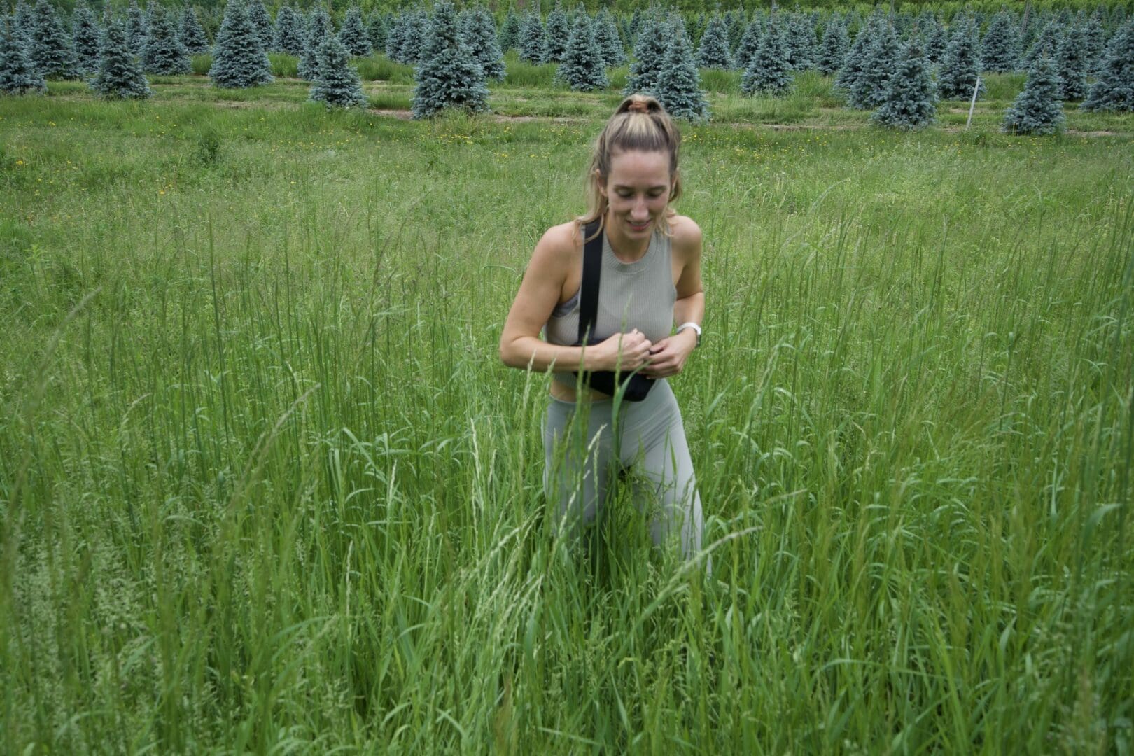 A woman in the grass holding onto some trees