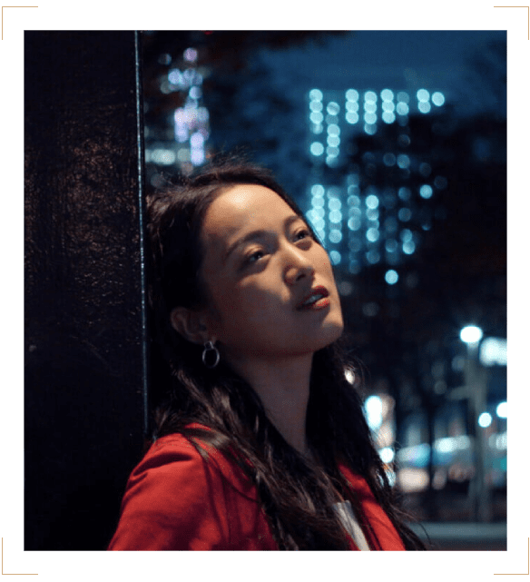 A woman in red jacket looking up at the sky.